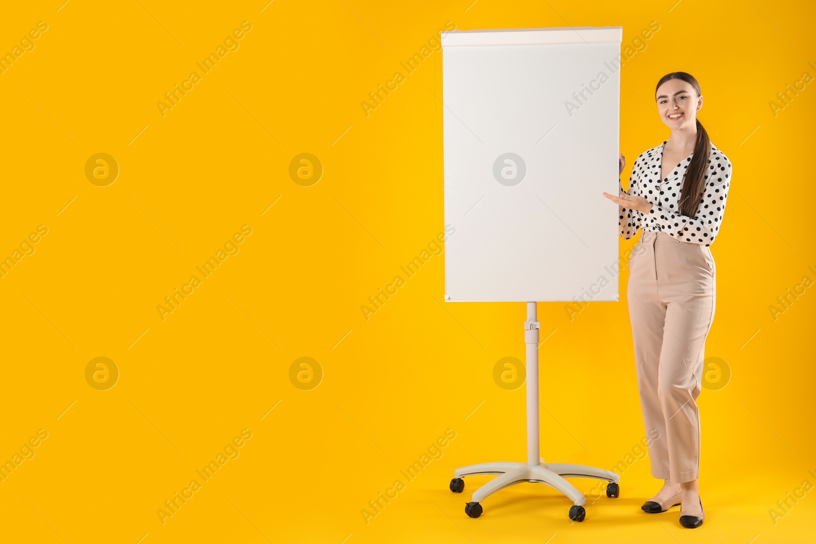 Photo of Happy woman near flip chart on orange background. Mockup for design