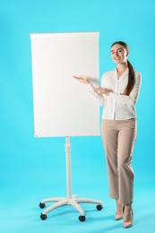 Happy woman near flip chart on light blue background. Mockup for design