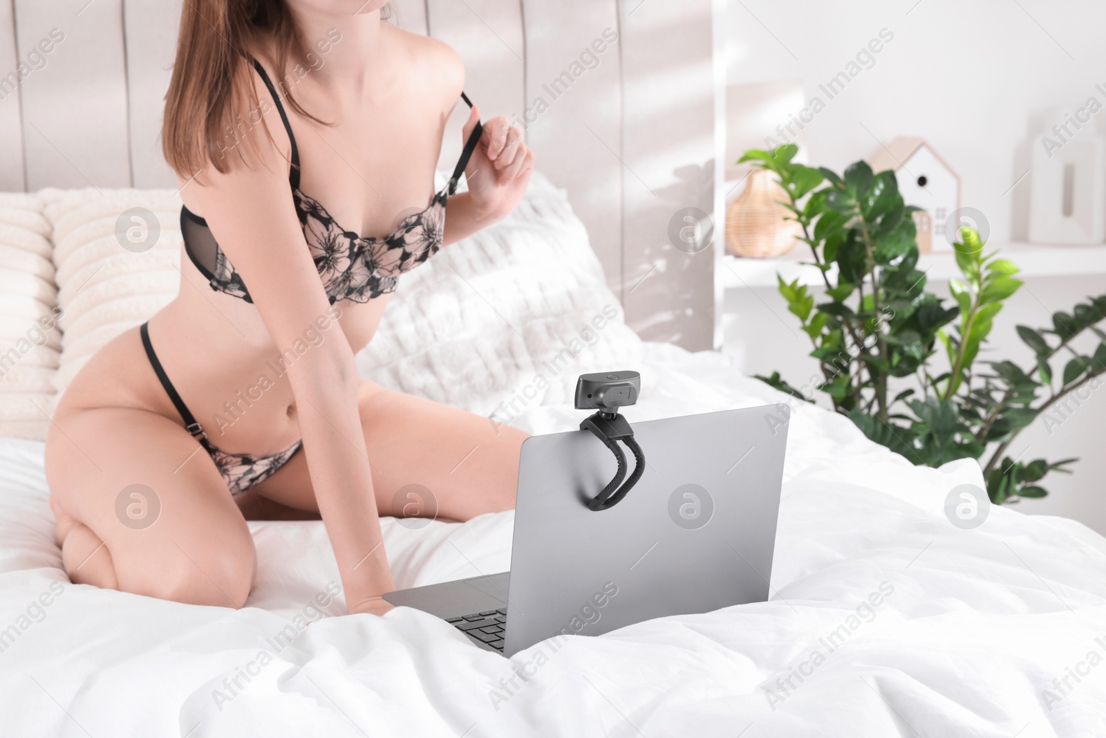 Photo of Prostitution. Webcam model in underwear streaming with laptop on bed indoors, closeup