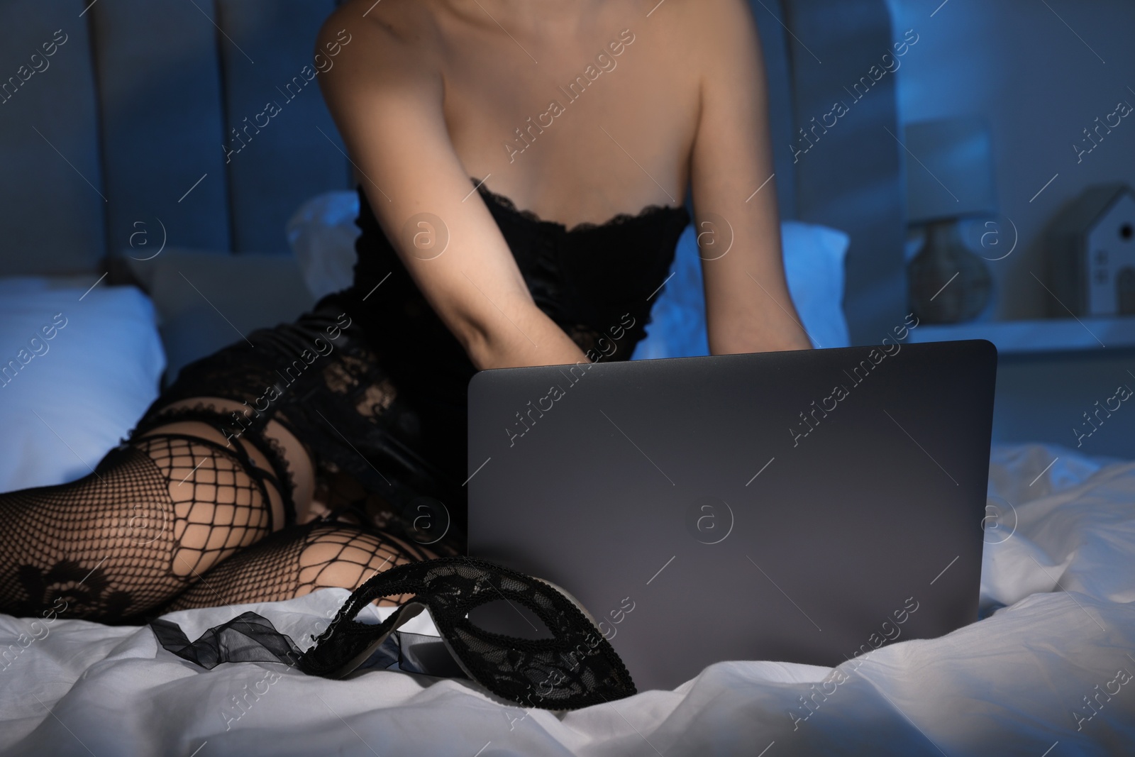 Photo of Prostitution. Webcam model working with laptop on bed, closeup