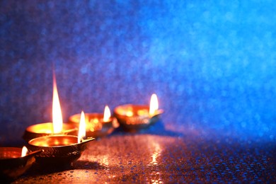 Photo of Diwali celebration. Diya lamps on color background. Space for text