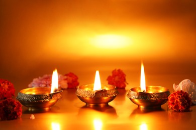 Photo of Diwali celebration. Diya lamps and beautiful flowers on golden background