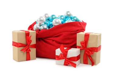 Photo of Red Santa Claus bag with baubles and gift boxes isolated on white