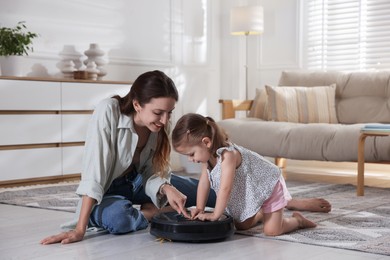 Photo of Mother and her daughter with robotic vacuum cleaner at home