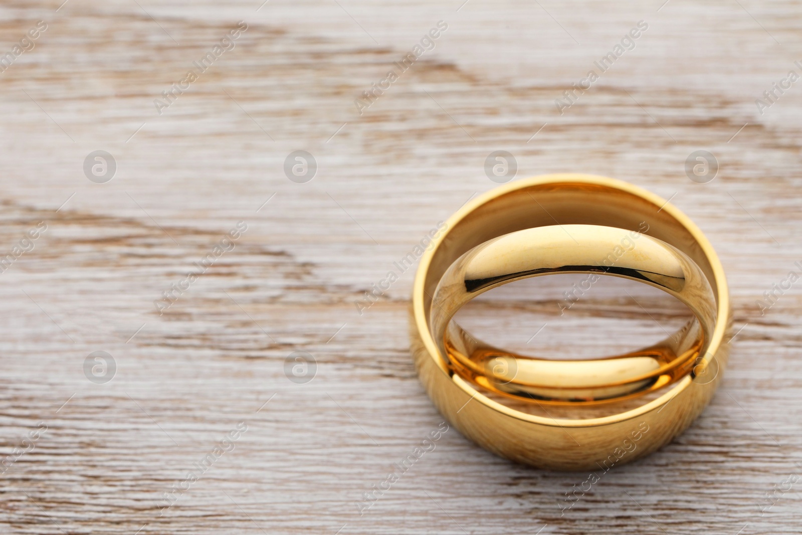 Photo of Beautiful golden wedding ring on wooden table, closeup. Space for text