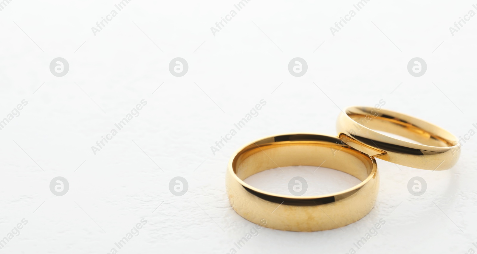 Photo of Beautiful golden wedding ring on white table, closeup. Space for text