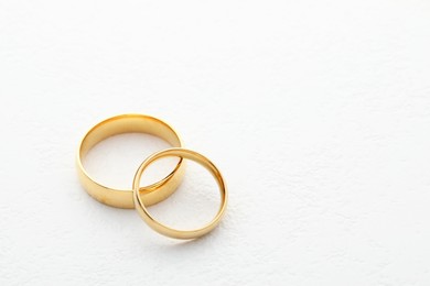 Photo of Beautiful golden wedding ring on white table, space for text