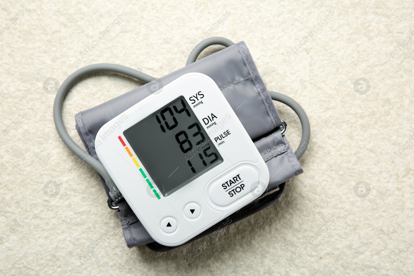 Photo of Blood pressure measuring device on light textured background, top view