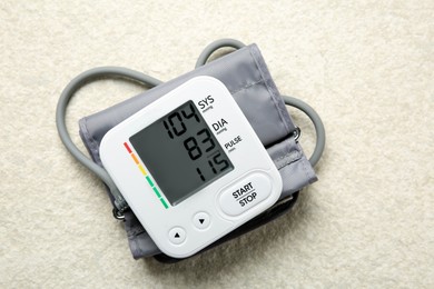 Blood pressure measuring device on light textured background, top view