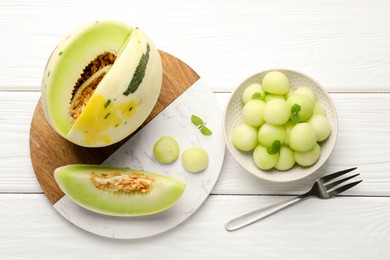 Photo of Melon balls in bowl and fresh fruit on white wooden table, flat lay