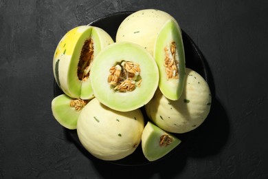 Photo of Fresh ripe honeydew melons on dark table, top view