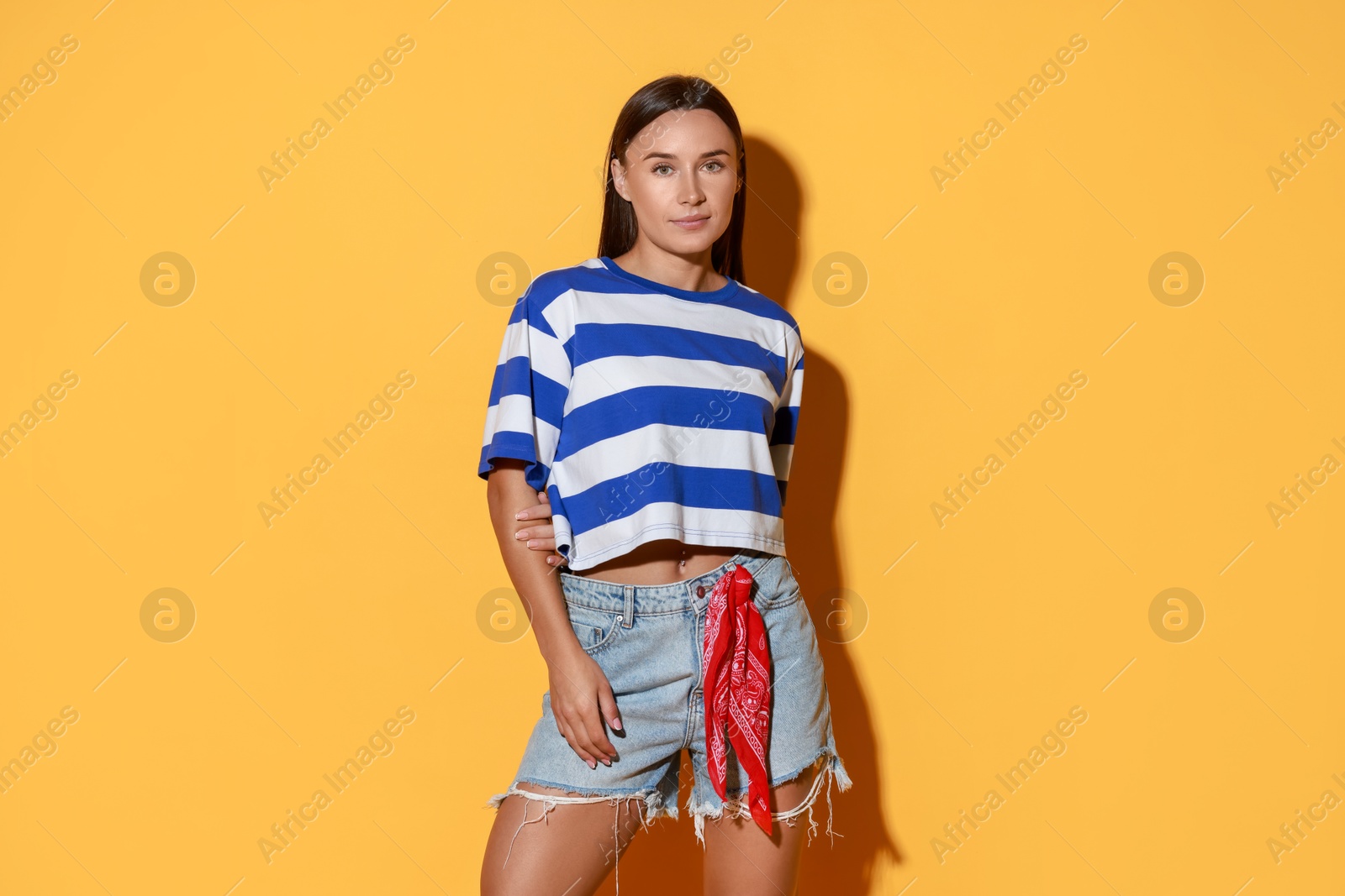 Photo of Beautiful woman wearing stylish denim shorts on yellow background