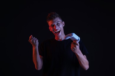 Happy young man with controller on black background