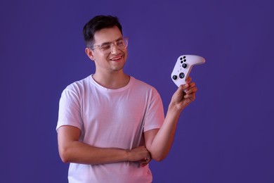 Young man with controller on violet background