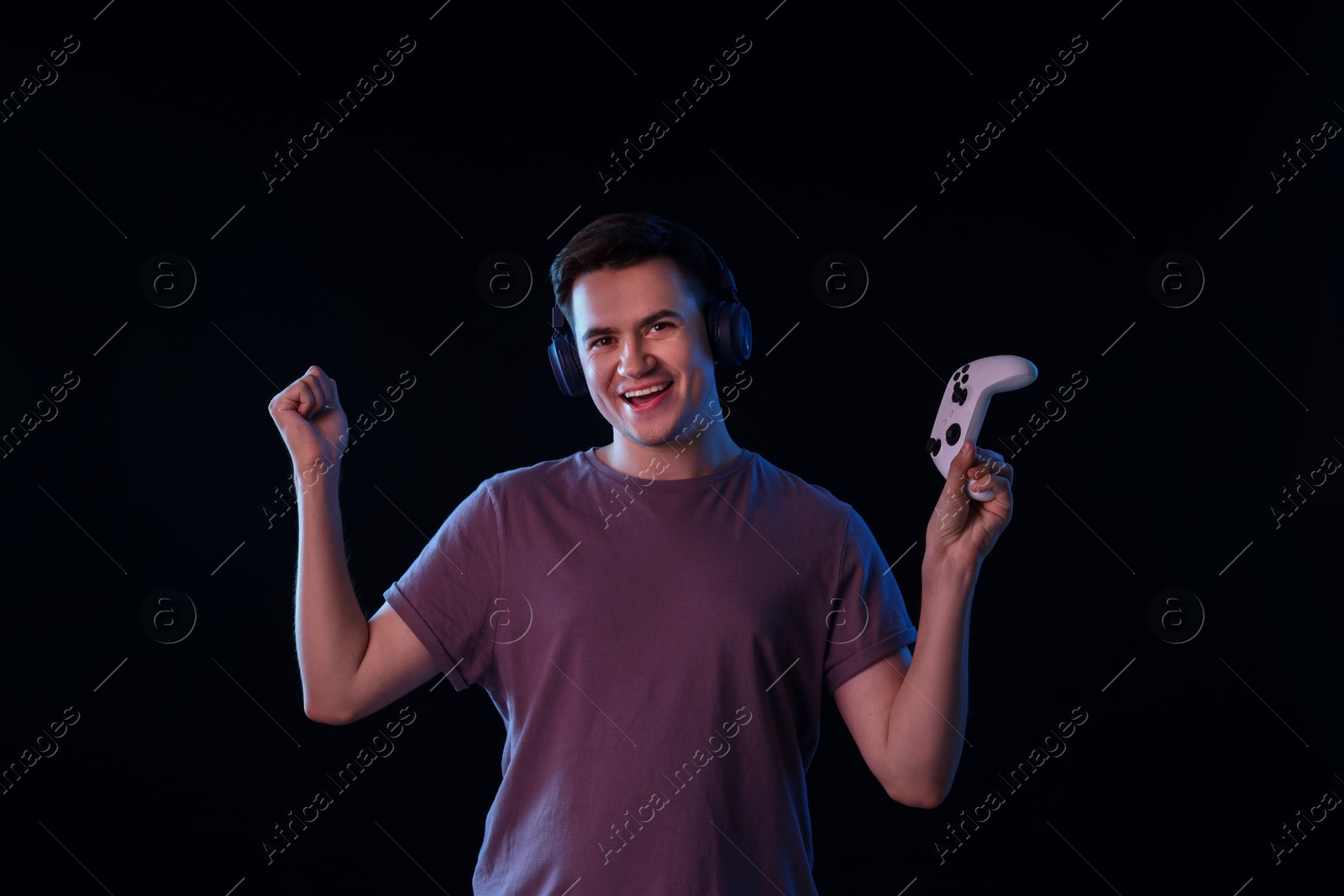 Photo of Young man in headphones with controller on black background