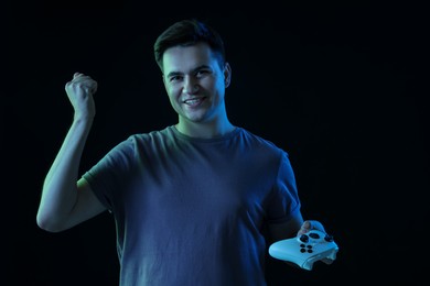 Photo of Happy young man with controller on black background