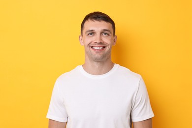 Smiling man with dental braces on yellow background