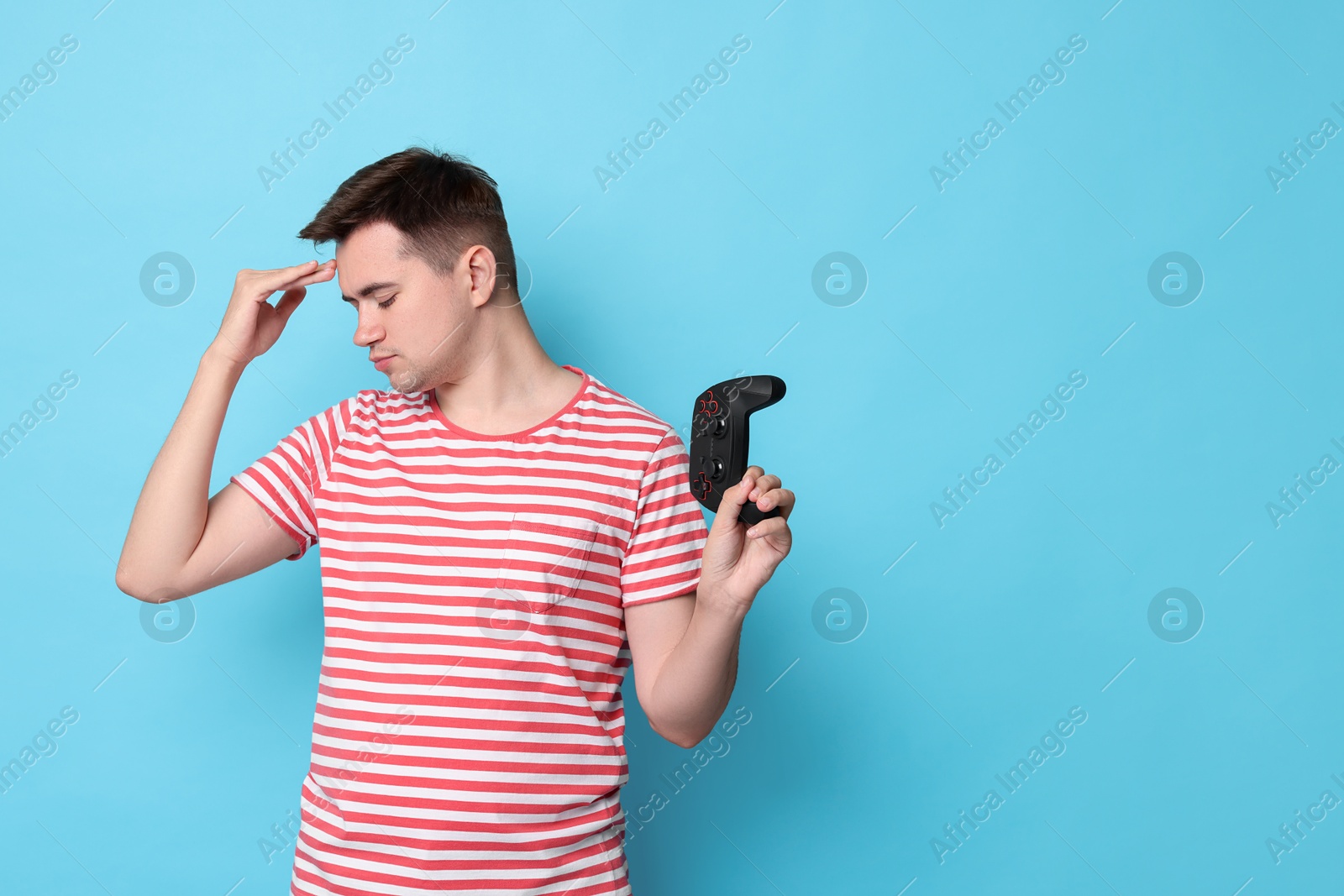 Photo of Young man with controller on light blue background, space for text