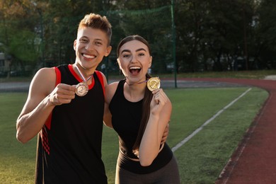 Happy winners with medals at stadium on sunny day. Space for text