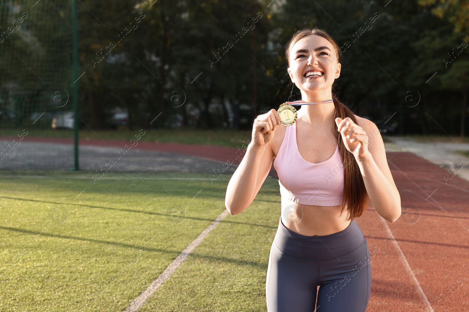 Photo of Happy winner with golden medal at stadium. Space for text