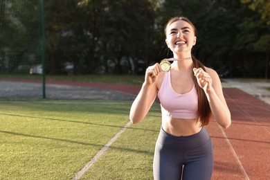 Happy winner with golden medal at stadium. Space for text