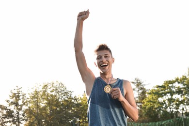 Happy young winner with golden medal outdoors