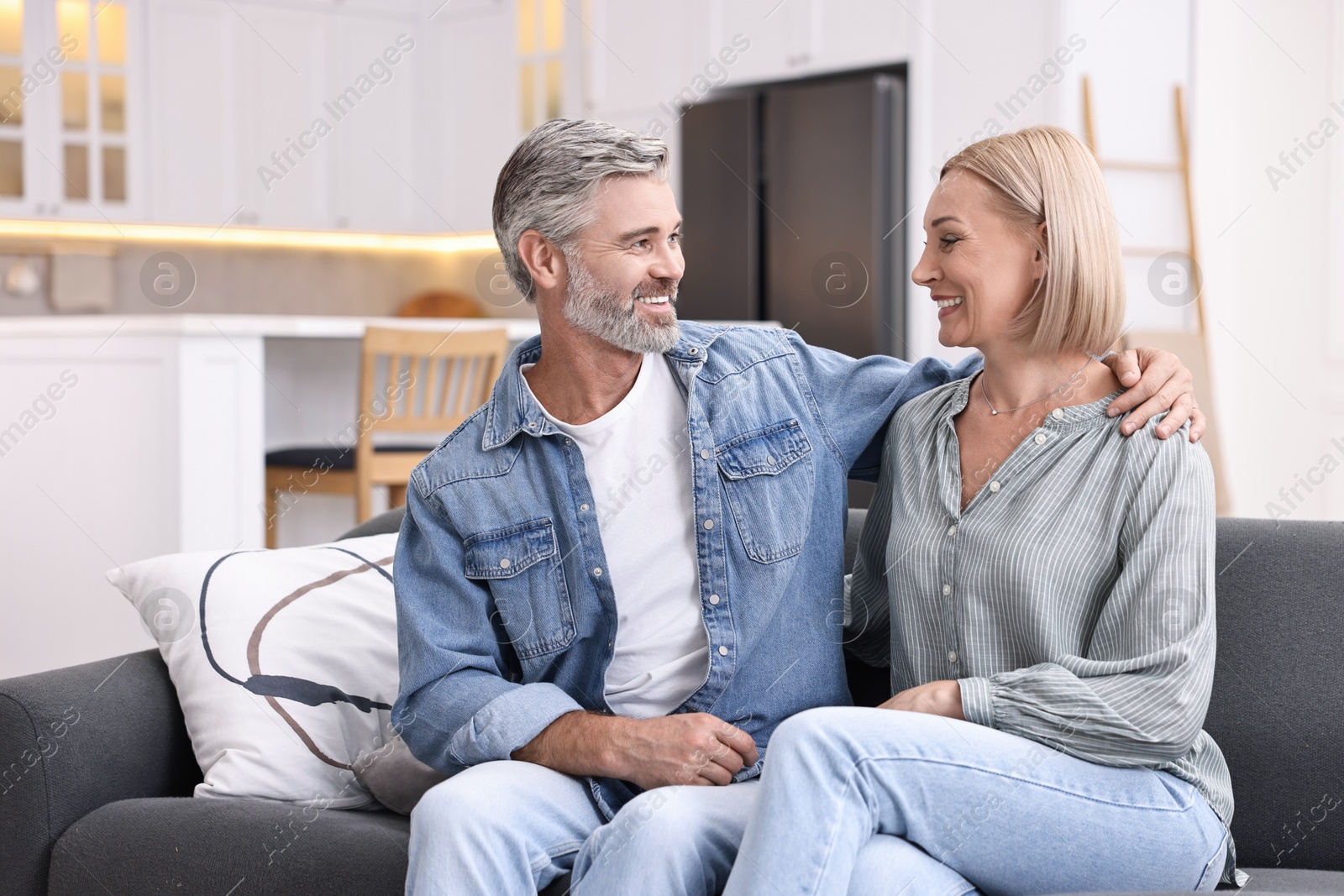 Photo of Happy middle aged couple on sofa in kitchen