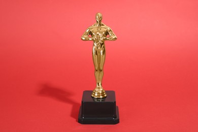 Photo of Golden trophy in shape of human figure on red background