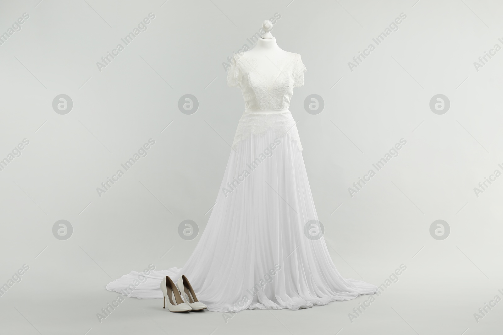 Photo of Mannequin with beautiful wedding dress and shoes on light grey background