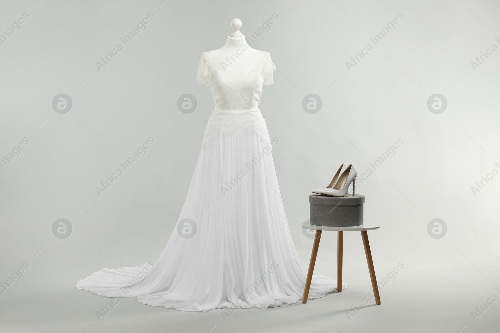 Photo of Mannequin with beautiful wedding dress and shoes on light grey background