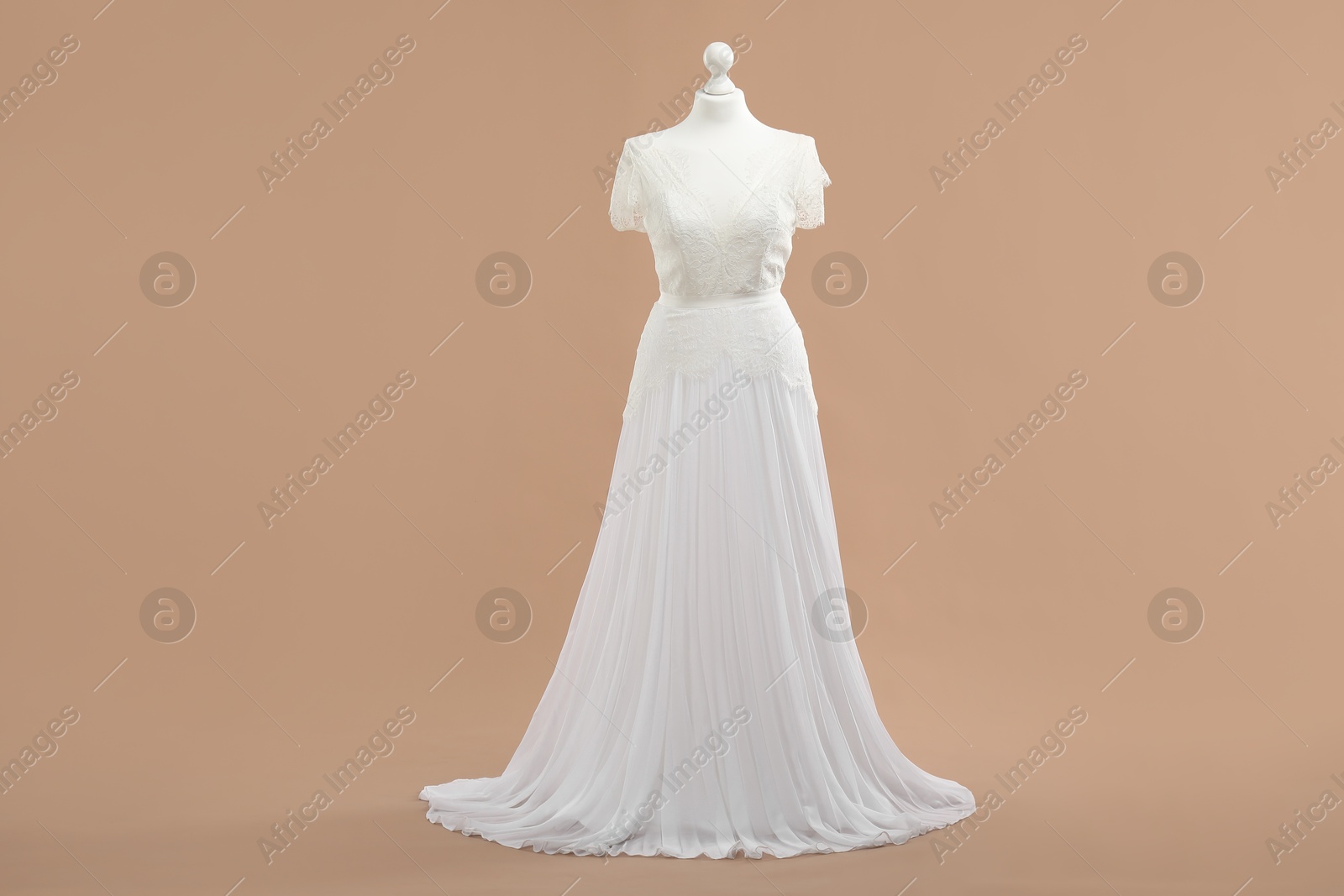 Photo of Mannequin with beautiful wedding dress on pale brown background