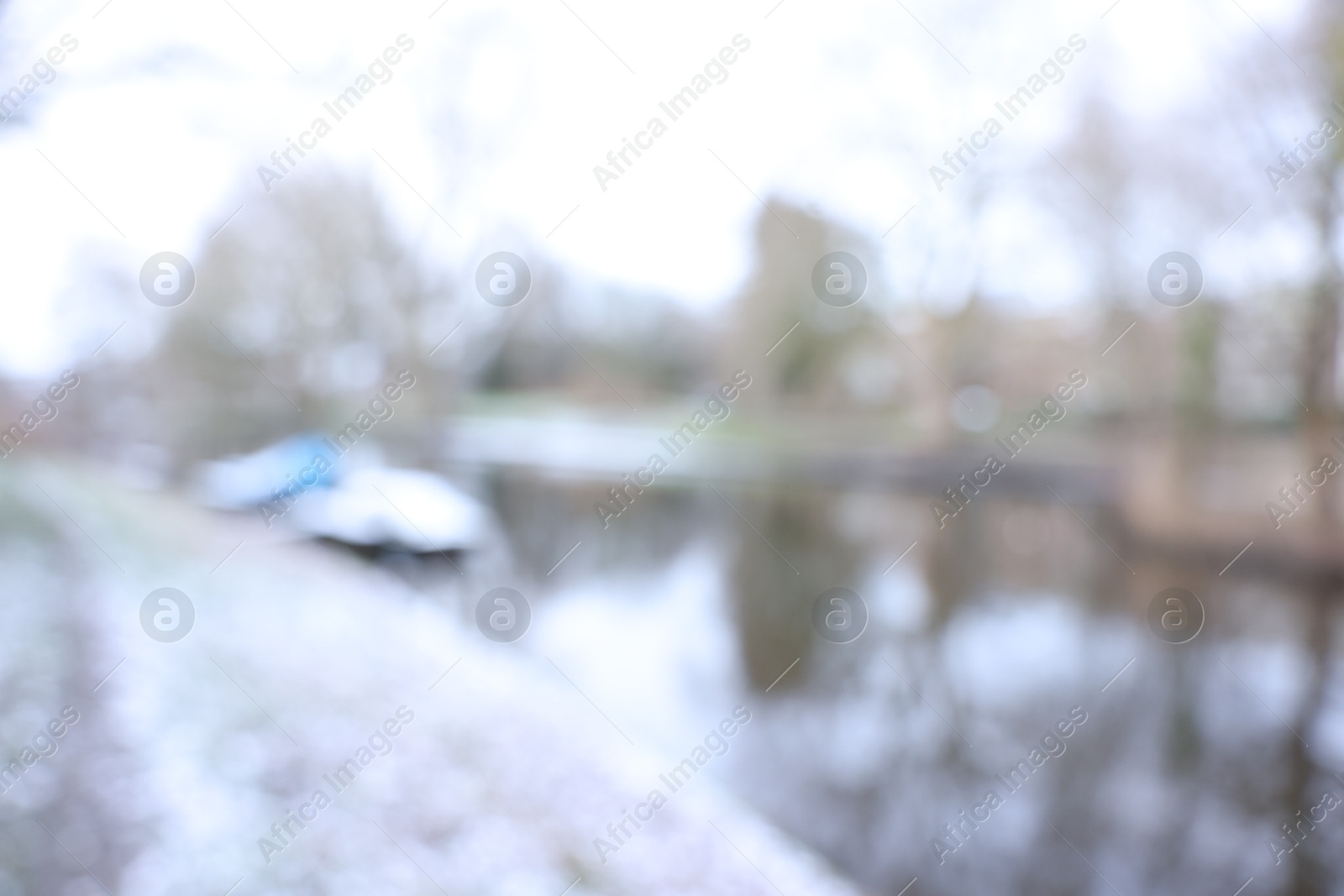 Photo of Blurred view of water canal and moored boat covered with snow on winter day