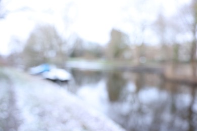 Photo of Blurred view of water canal and moored boat covered with snow on winter day