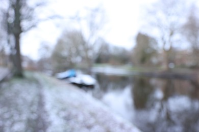 Photo of Blurred view of water canal and moored boat covered with snow on winter day