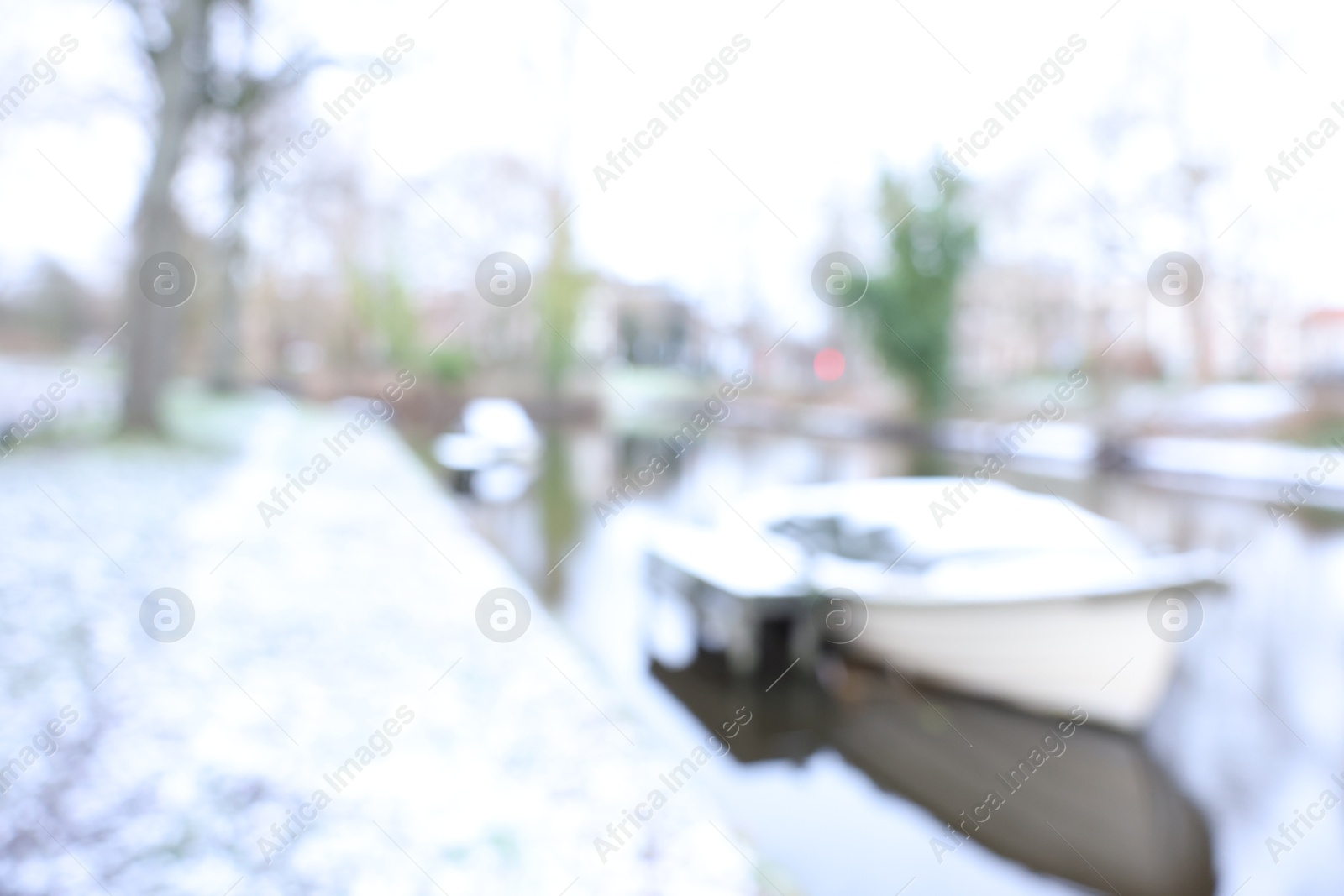 Photo of Blurred view of water canal and moored boat covered with snow on winter day