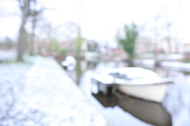 Photo of Blurred view of water canal and moored boat covered with snow on winter day