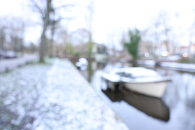 Photo of Blurred view of water canal and moored boat covered with snow on winter day