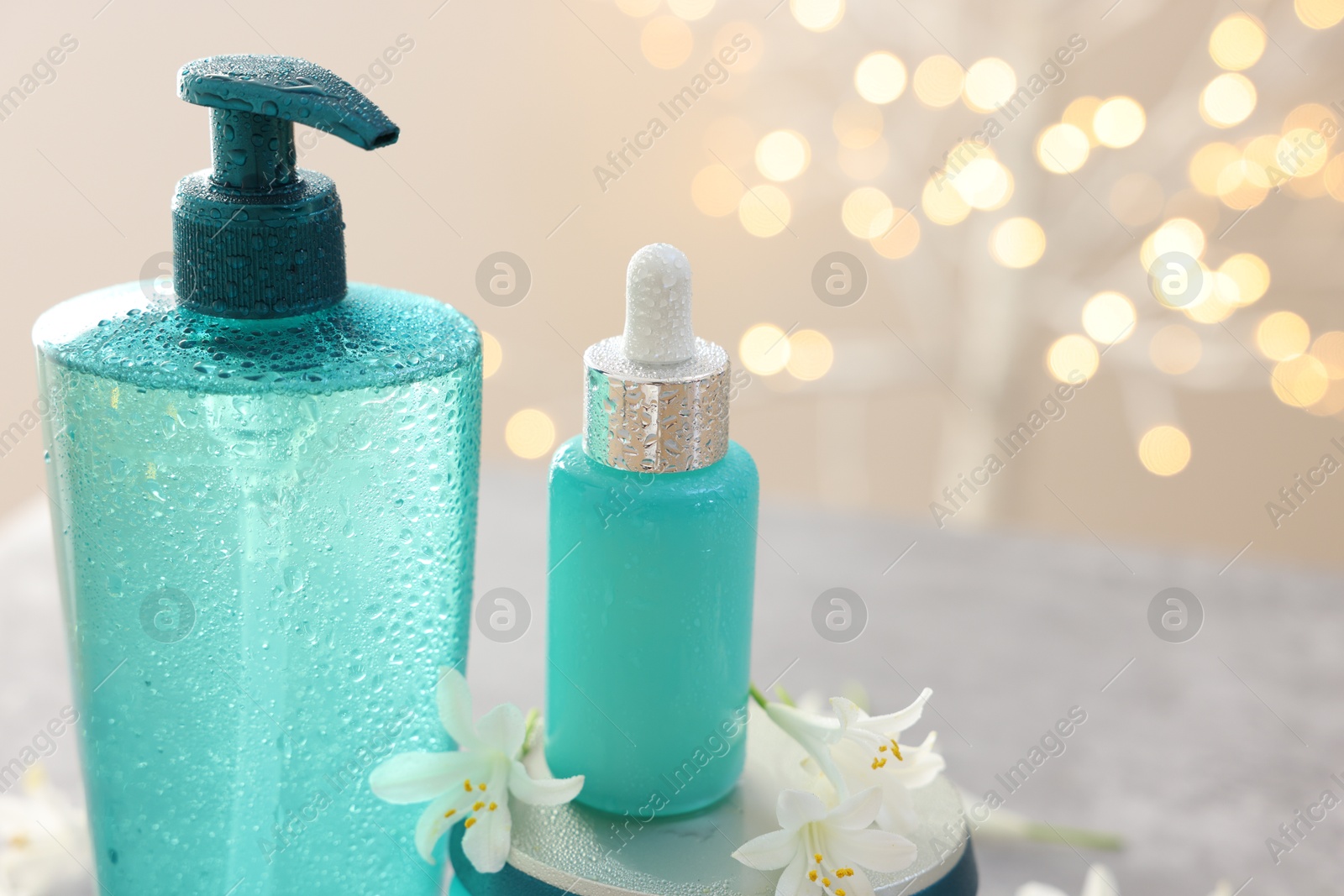 Photo of Cosmetic products and jasmine flowers against beige background with blurred lights, closeup