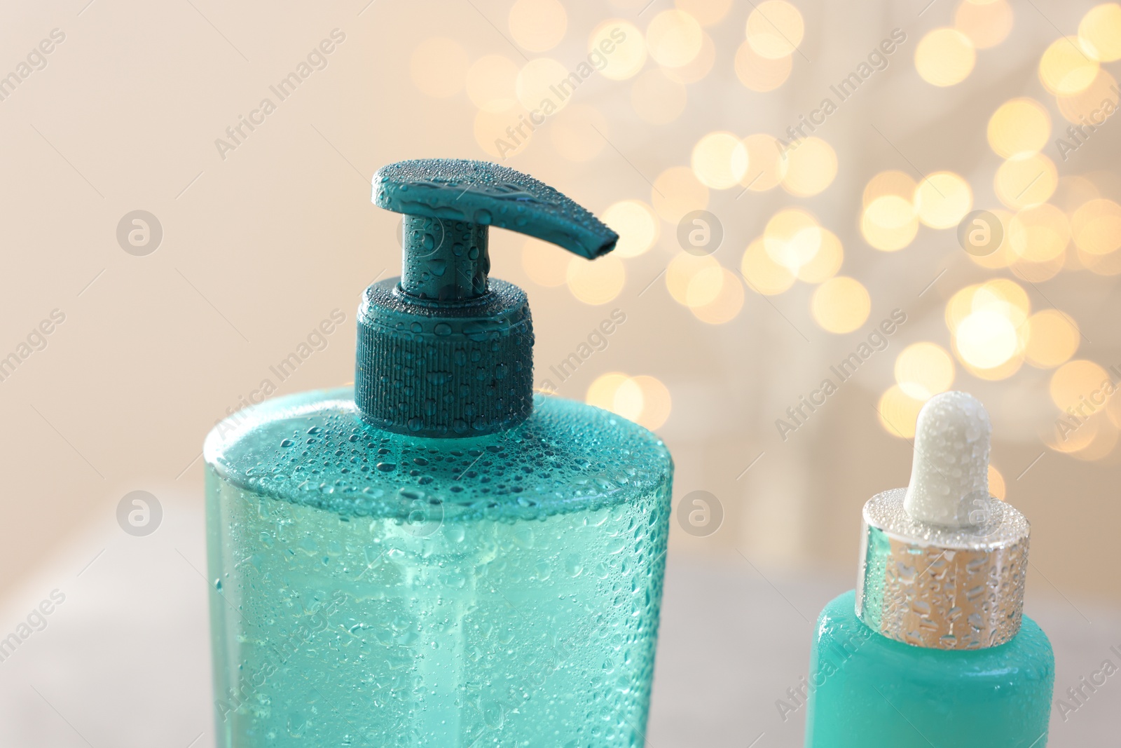 Photo of Cosmetic products against beige background with blurred lights, closeup