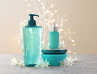 Photo of Cosmetic products and beautiful jasmine flowers on grey table