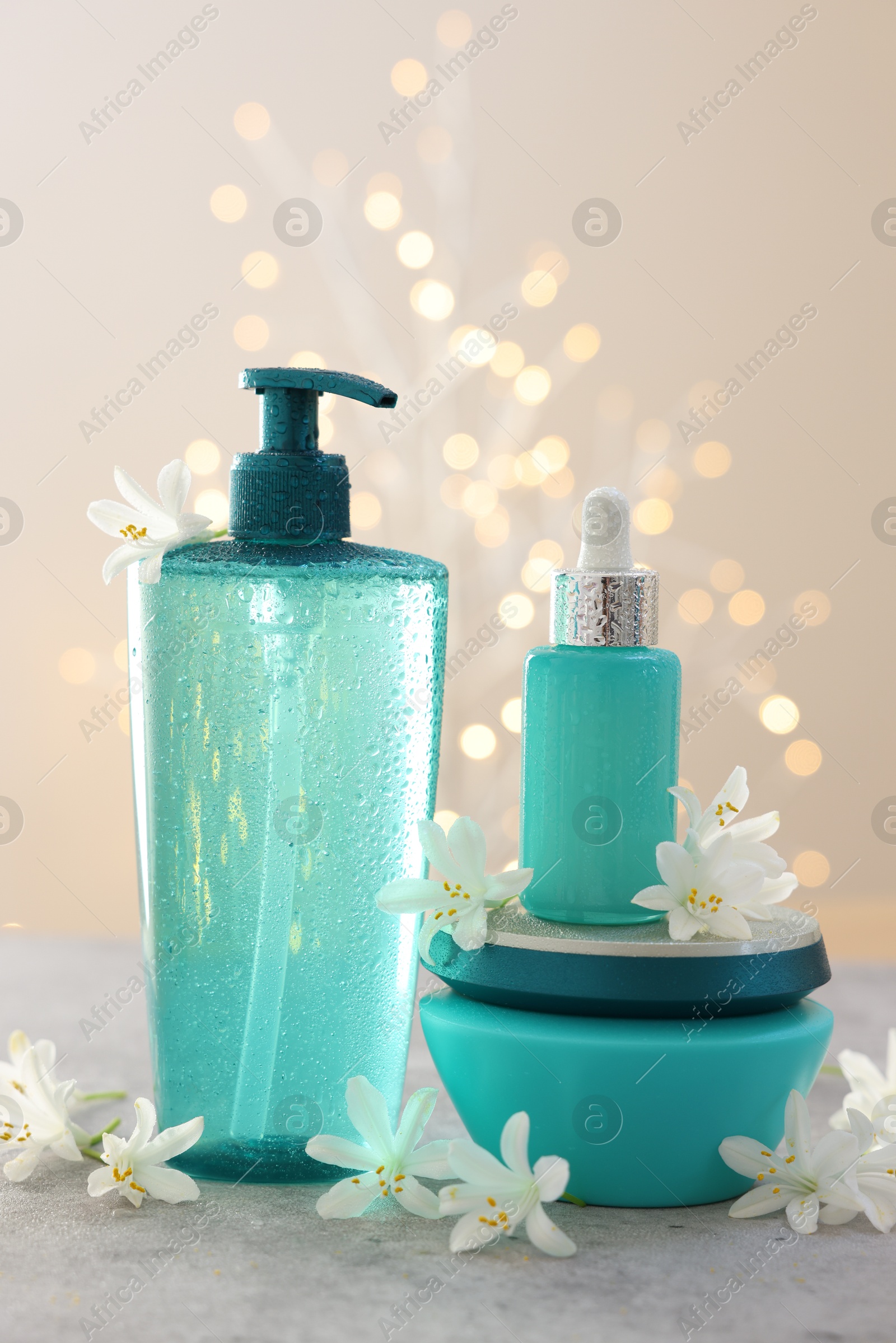 Photo of Cosmetic products and beautiful jasmine flowers on grey table