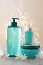 Photo of Cosmetic products and beautiful jasmine flowers on grey table