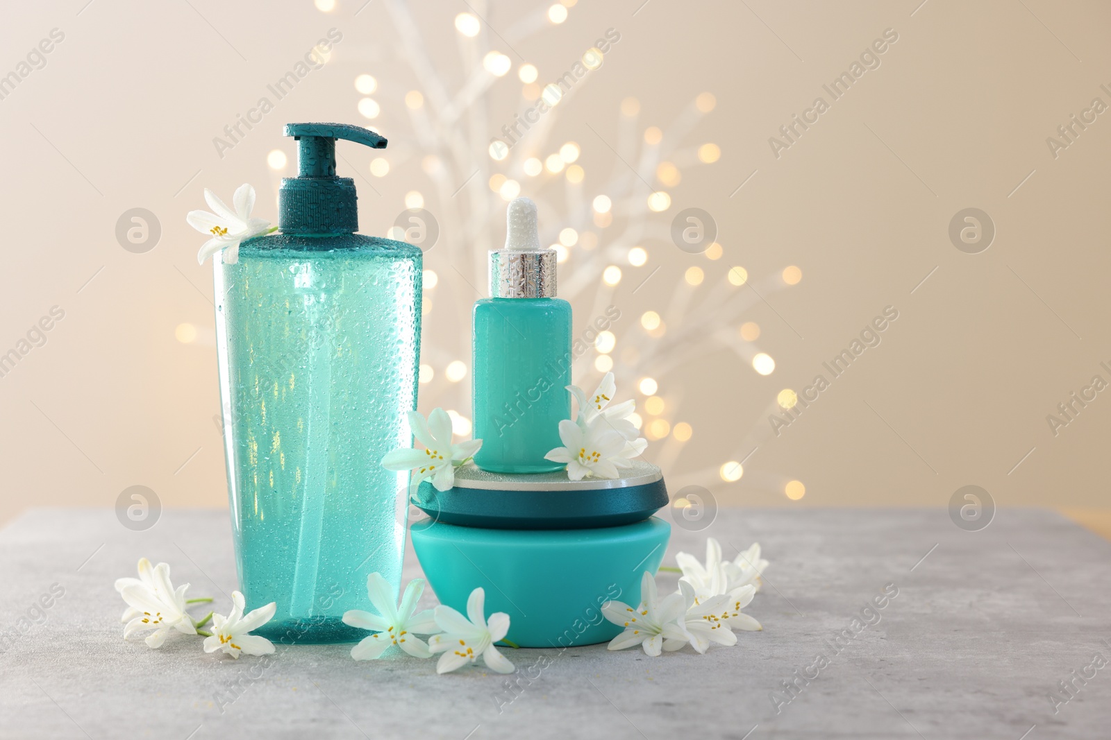 Photo of Cosmetic products and beautiful jasmine flowers on grey table