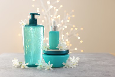 Photo of Cosmetic products and beautiful jasmine flowers on grey table