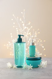 Photo of Cosmetic products and beautiful jasmine flowers on grey table