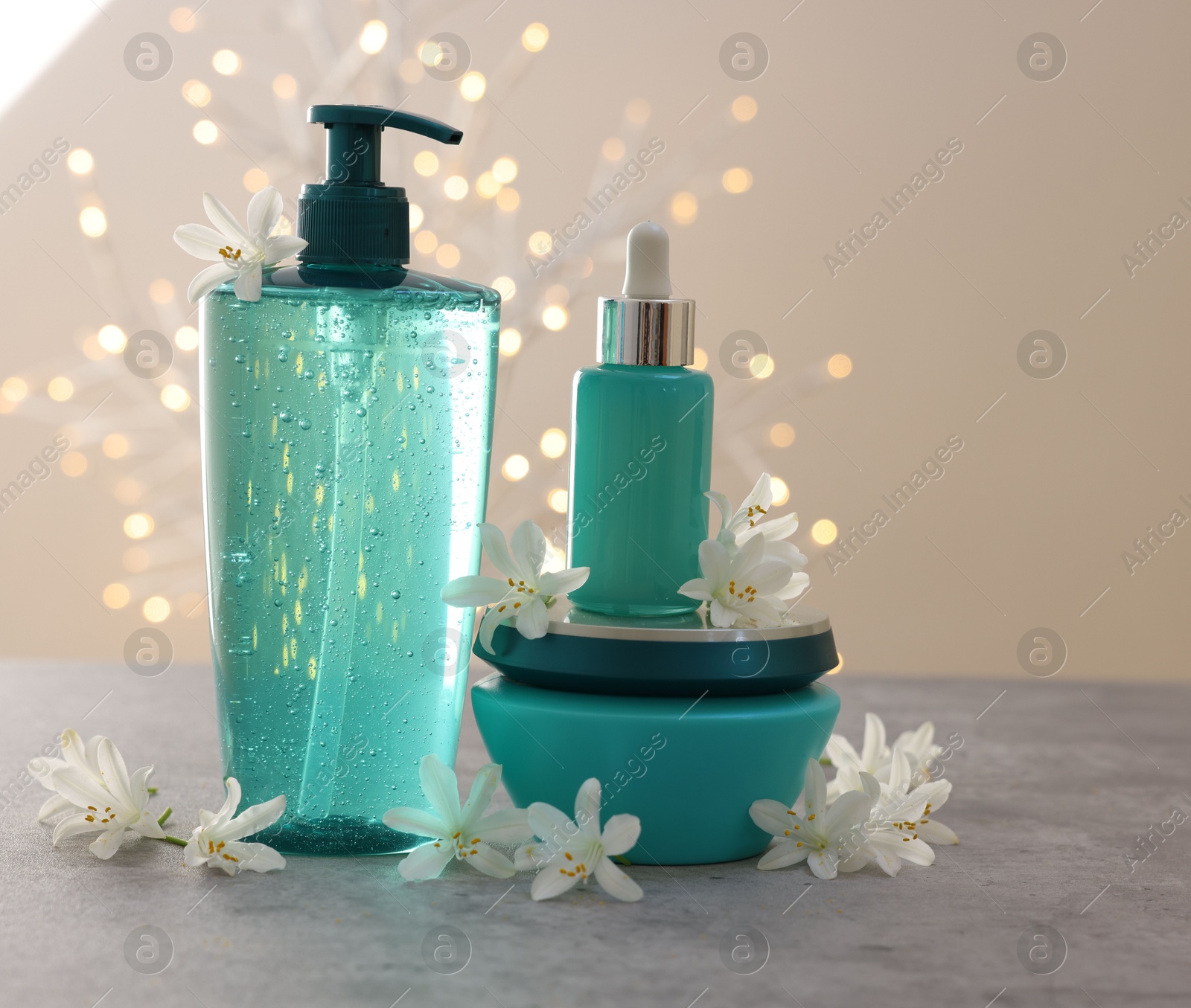 Photo of Cosmetic products and beautiful jasmine flowers on grey table