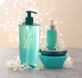 Photo of Cosmetic products and beautiful jasmine flowers on grey table