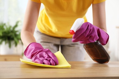 Woman cleaning table with rag and spray at home, closeup