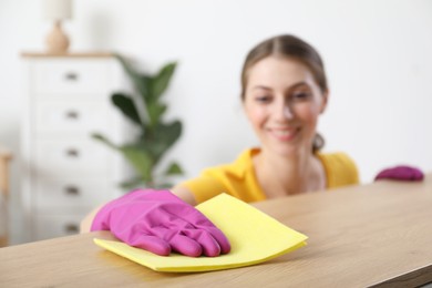 Woman cleaning table with rag at home, selective focus