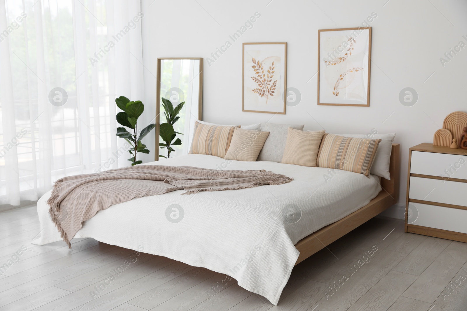 Photo of Large bed, houseplant and full-length mirror near window in room. Stylish bedroom interior